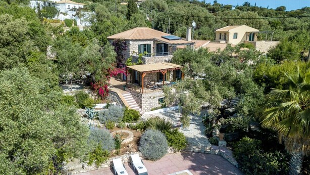 Una villa con piscina, senderos de piedra y abundante vegetación.