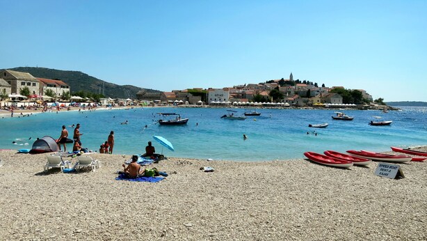 A beach with people sunbathing, boats, and a sign for speed boat rental. - Primosten Hills - North by Interhome (Primošten)