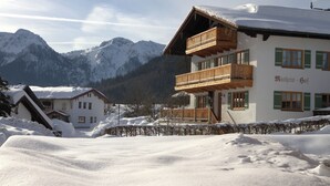 A chalet-style building with a wooden balcony, surrounded by snow-covered mountains. - Vacation apartment Guat'kammer (Inzell)