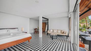 A modern hotel room with a checkered floor, a bed, a sofa, and a dining area.