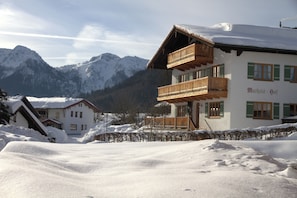 Ein Chalet mit hölzerner Balkon, umgeben von schneebedeckten Bergen.