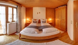 A wooden-framed bed with two bedside tables, a wall-mounted light fixture, and a wooden wardrobe. - Vacation apartment Stub'nkammer (Inzell)