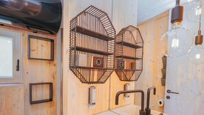 Un bagno con parete in legno, lavabo con rubinetto moderno e dispenser di asciugamani.
