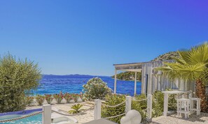 A poolside area with a view of the sea, a wooden pergola, and a seating area with a table and chairs. - Buqez - Villa 18 by Interhome (Pakoštane/Drage)