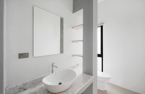 Een moderne badkamer met een wit wastafel, een spiegel en een toilet.
