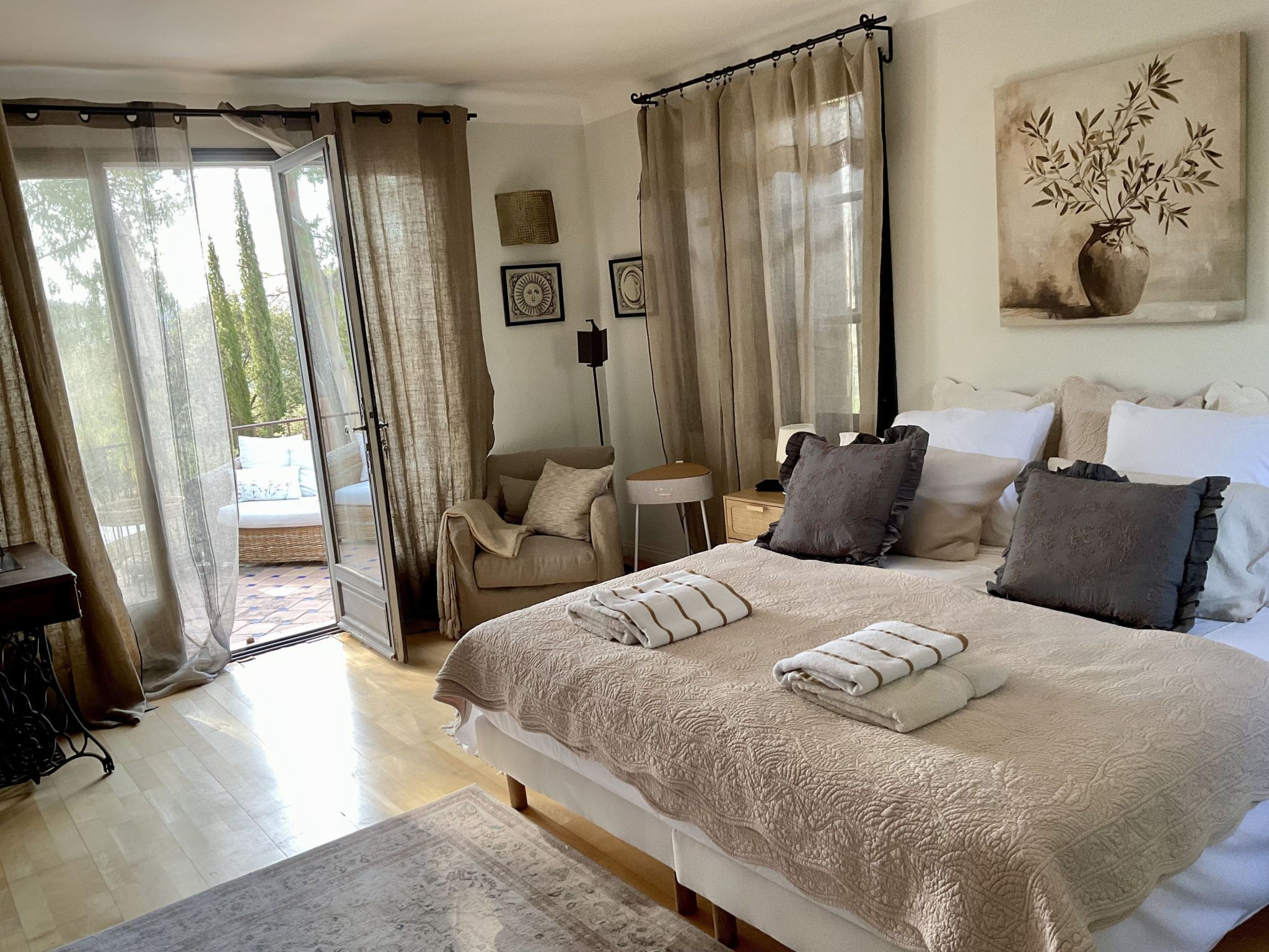 A bedroom with a large bed, a desk, a chair, and a view of the outdoors.