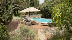 A backyard with a swimming pool, lounge chairs, and a stone wall. - LA CADENIERE by Interhome (Carces)