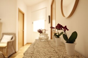 A hallway with a patterned rug, a wicker chair, and potted plants. - Luxury Apartment in Museum Mile 2 (Madrid)