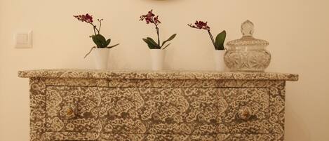 A patterned cabinet with three potted plants and a decorative jar.
