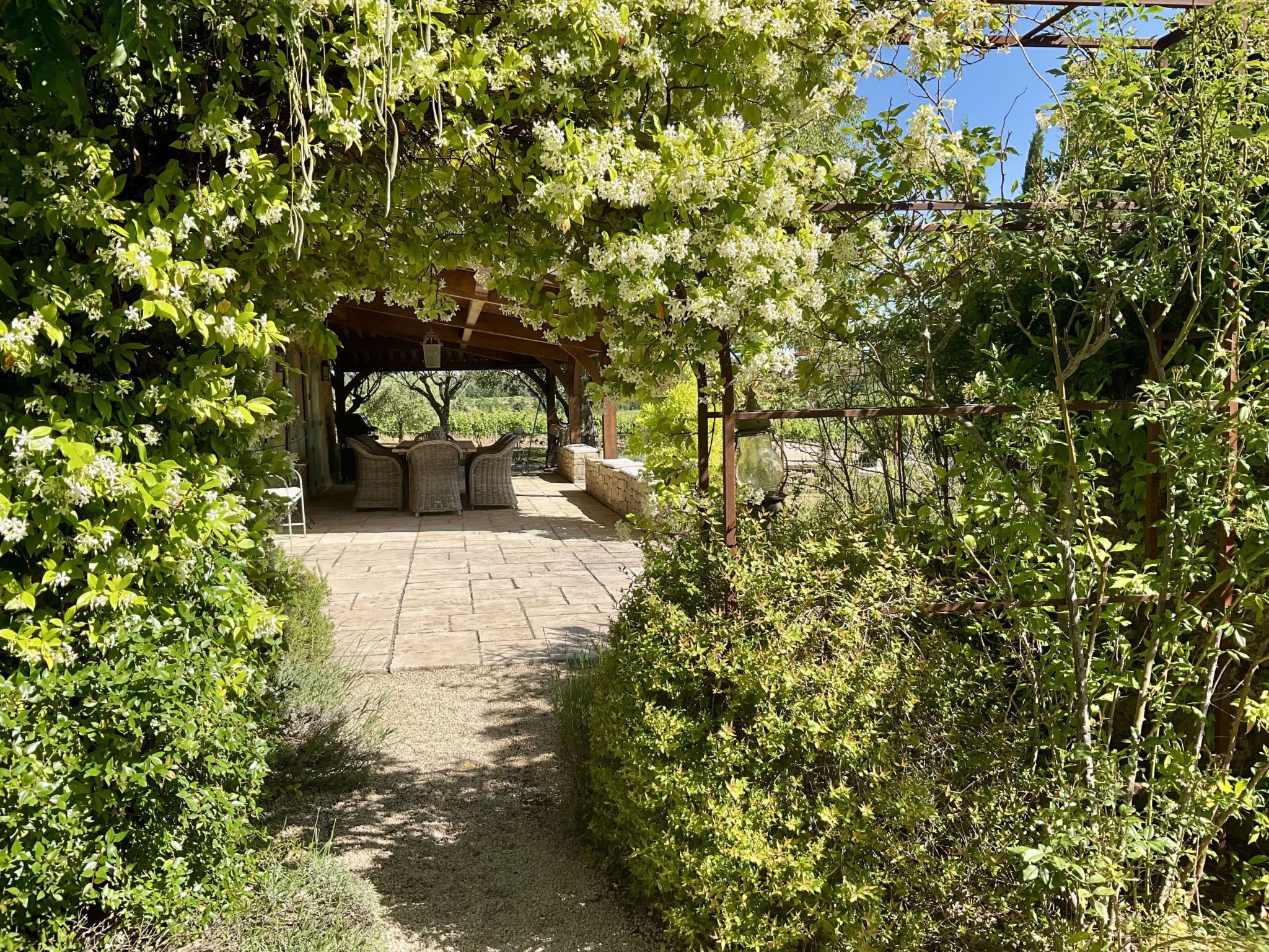 A covered outdoor seating area with stone flooring and a pergola structure.