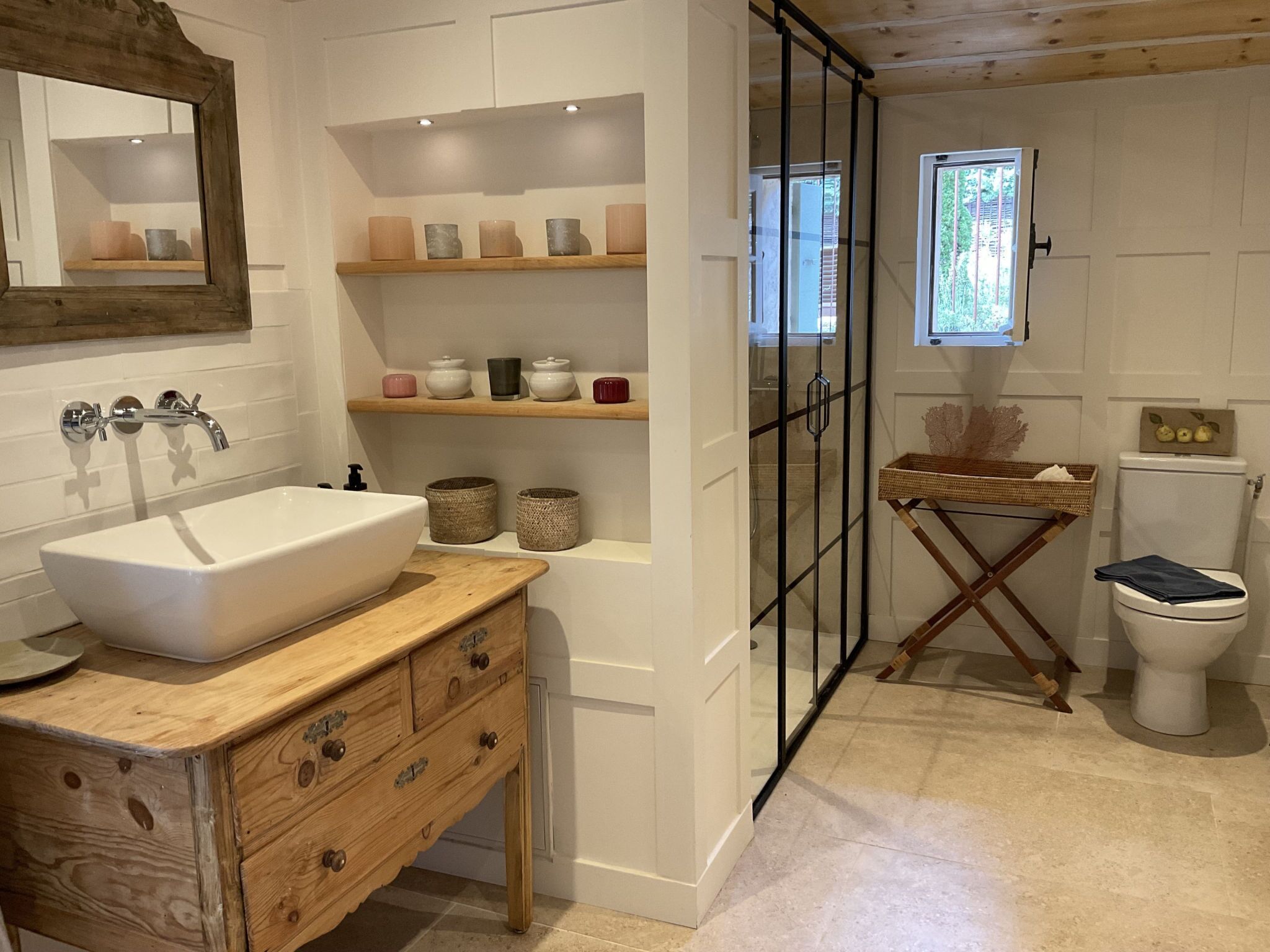 Ein Badezimmer mit einem Holzbadezimmer-Möbelstück, einem weißen Waschbecken, einer Duschkabine aus Glas und einer Toilette.