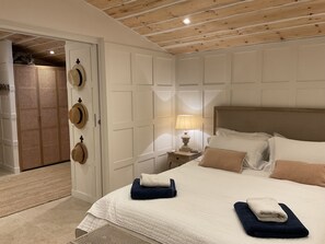 Ein Hotelzimmer mit Bett, Nachttisch, Lampe und einer Tür mit Hüten.
