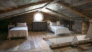 A loft bedroom with two beds, a round skylight, and a sailboat model. - Vacation home  by Interhome (Carces)