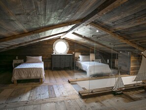 Quarto em estilo loft com duas camas, um domo redondo e uma réplica de veleiro.