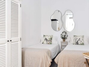 A room with two beds, a small bedside table with a plant, and two wall-mounted mirrors. - Prado Museum 3 dorms AC (Madrid)