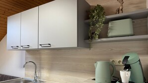 A modern kitchen with a built-in dishwasher, a kettle, and a coffee machine. - Vacation apartment BergZeit for max. 4 adults (Chieming)
