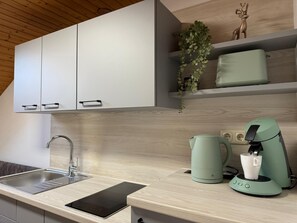 A modern kitchen with a built-in dishwasher, a kettle, and a coffee machine. - Vacation apartment BergZeit for max. 4 adults (Chieming)