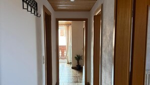 A hallway with wooden doors, a tiled floor, and a ceiling with a skylight. - Vacation apartment BergZeit for max. 4 adults (Chieming)