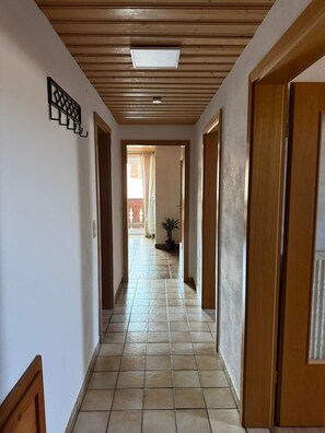 A hallway with wooden doors, a tiled floor, and a ceiling with a skylight. - Vacation apartment BergZeit for max. 4 adults (Chieming)