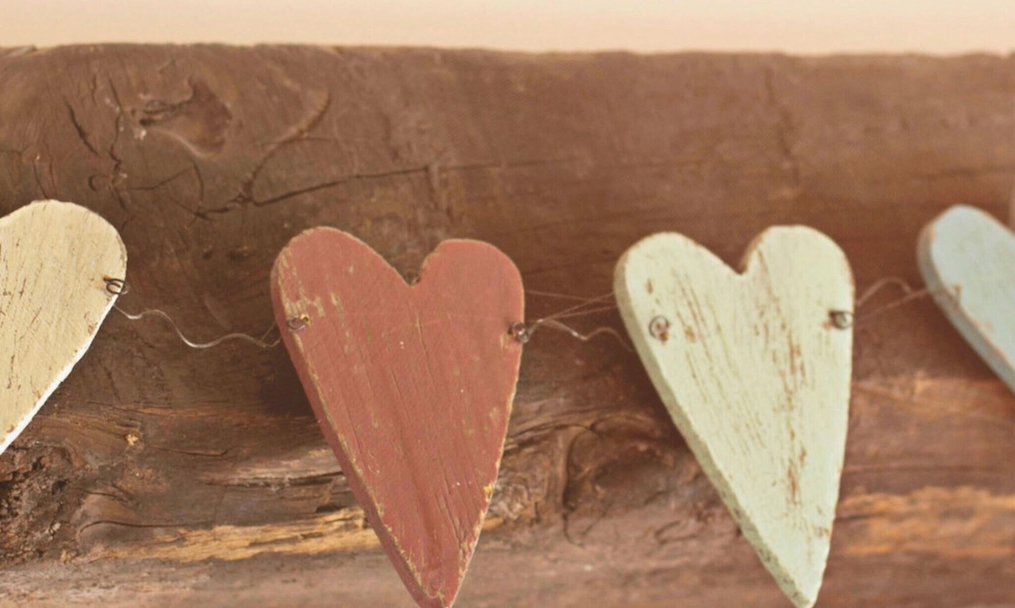 A wooden surface with three heart-shaped objects attached by wire.