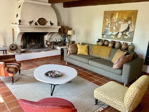 Ein gemütliches Wohnzimmer mit Kamin, einer Couch, einem Couchtisch und Dekorationselementen.