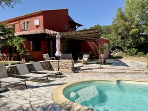 Eine rote Villa mit Swimmingpool, Außenbereich und einer Steinterrasse.