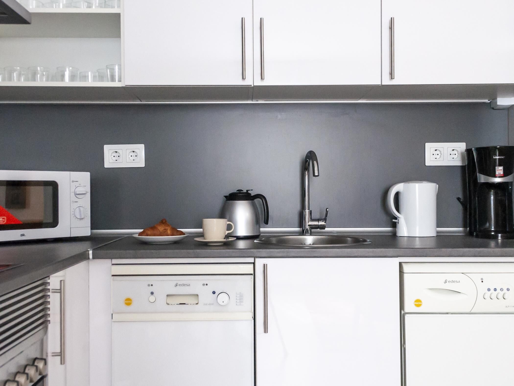 A kitchen with a microwave, coffee maker, sink, and a dishwasher.
