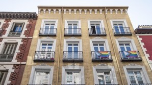 Ein mehrstöckiges Gebäude mit gelber Fassade, weißen Fensterrahmen und schwarzen Balkonläufungen.