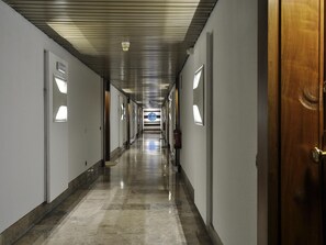 A long, narrow hotel corridor with a polished floor, recessed lighting, and a wooden door on the right. - Luxury Apartment in Plaza de Colon (Madrid)