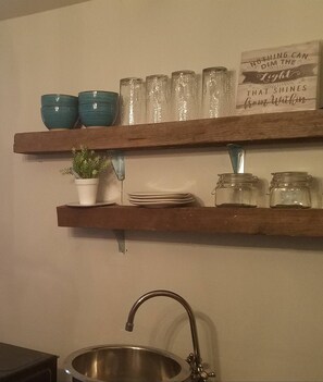 A kitchen with two wooden shelves, a sink, and a potted plant. - Adorable tiny house near Mercedes Benz Stadium (Atlanta)