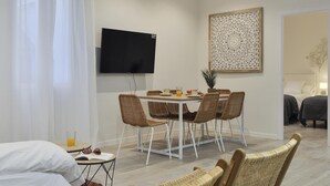 Un soggiorno moderno con angolo pranzo, una TV a schermo piatto e un elemento decorativo a parete.