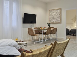 Ein modernes Wohnzimmer mit Essbereich, einem Flachbildfernseher und einer Wanddekoration.