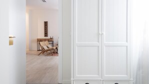 Un armadio bianco con due cassetti, una sedia di legno e un cartello fissato al muro.