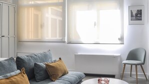 A modern living room with a grey sofa, a round coffee table, and a grey armchair. - Fantastic Studio in Puerta del Sol (Madrid)