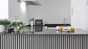 A modern kitchen with a built-in microwave, a stainless steel range hood, a sink, and a countertop with a striped pattern. - Fantastic Studio in Puerta del Sol (Madrid)