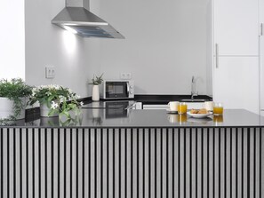 A modern kitchen with a built-in microwave, a stainless steel range hood, a sink, and a countertop with a striped pattern. - Fantastic Studio in Puerta del Sol (Madrid)