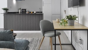 A modern kitchen with a microwave, toaster, and kettle, a dining area with a table and chairs, and a living room with a sofa and a TV mounted on the wall. - Fantastic Studio in Puerta del Sol (Madrid)