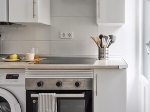 A kitchen with a built-in oven, a washing machine, and a coffee maker. - Suite Estudio en Bravo Murillo (Madrid)