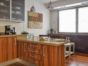A kitchen with wooden cabinets, a coffee maker, a potted plant, and a window with a view. - Luxury Studio in Plaza de Colon (Madrid)