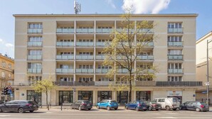 A multi-story building with balconies, a parking lot, and a storefront. - Stylish Apartment with Balcony | Center of Warsaw (Warszawa)
