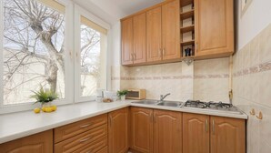 A kitchen with wooden cabinets, a white countertop, a sink, and a stove. - Stylish Apartment with Balcony | Center of Warsaw (Warszawa)