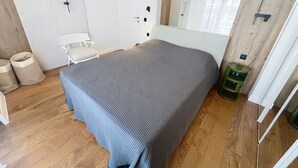 A bedroom with a bed, a chair, a door, and a mirror. - Apartment  by Interhome (Cannes)