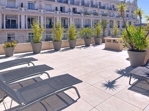 Eine Dachterrasse mit Sitzgelegenheiten und Pflanzen in Töpfen.