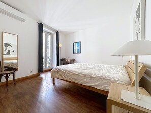 A bedroom with a bed, a chair, a desk, a lamp, a window with curtains, and a painting on the wall. - 1 bedroom, fantastic view on the port. 269 by Interhome (Cannes)