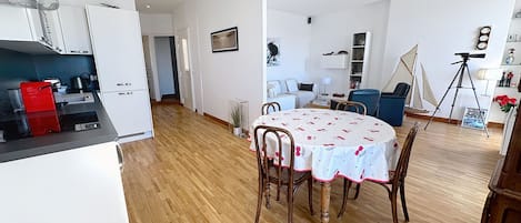 A modern kitchen with white cabinets, a red toaster, and a dining area with a round table and chairs.