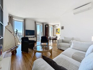 A modern living room with a flat-screen TV, a large window, and a sailboat model. - 1 bedroom, fantastic view on the port. 269 by Interhome (Cannes)