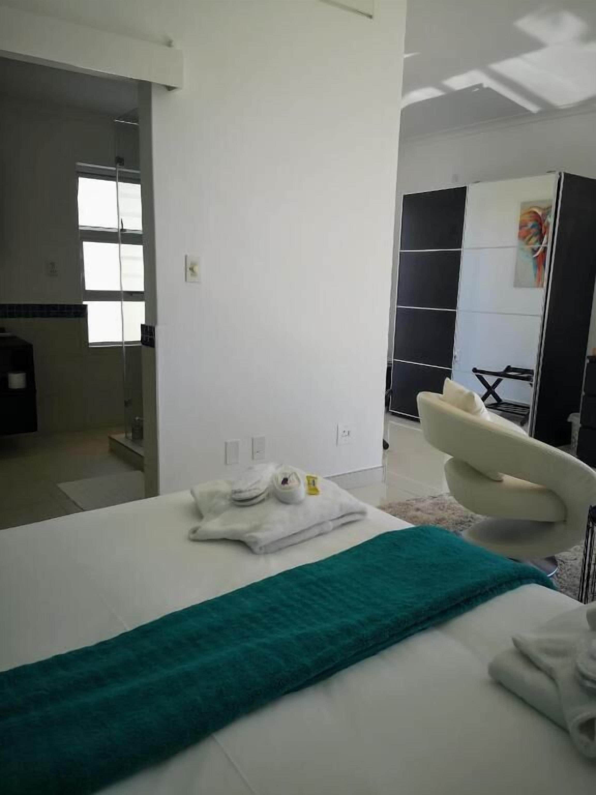 A modern hotel room with a bed, a bathroom, and a view of the city.