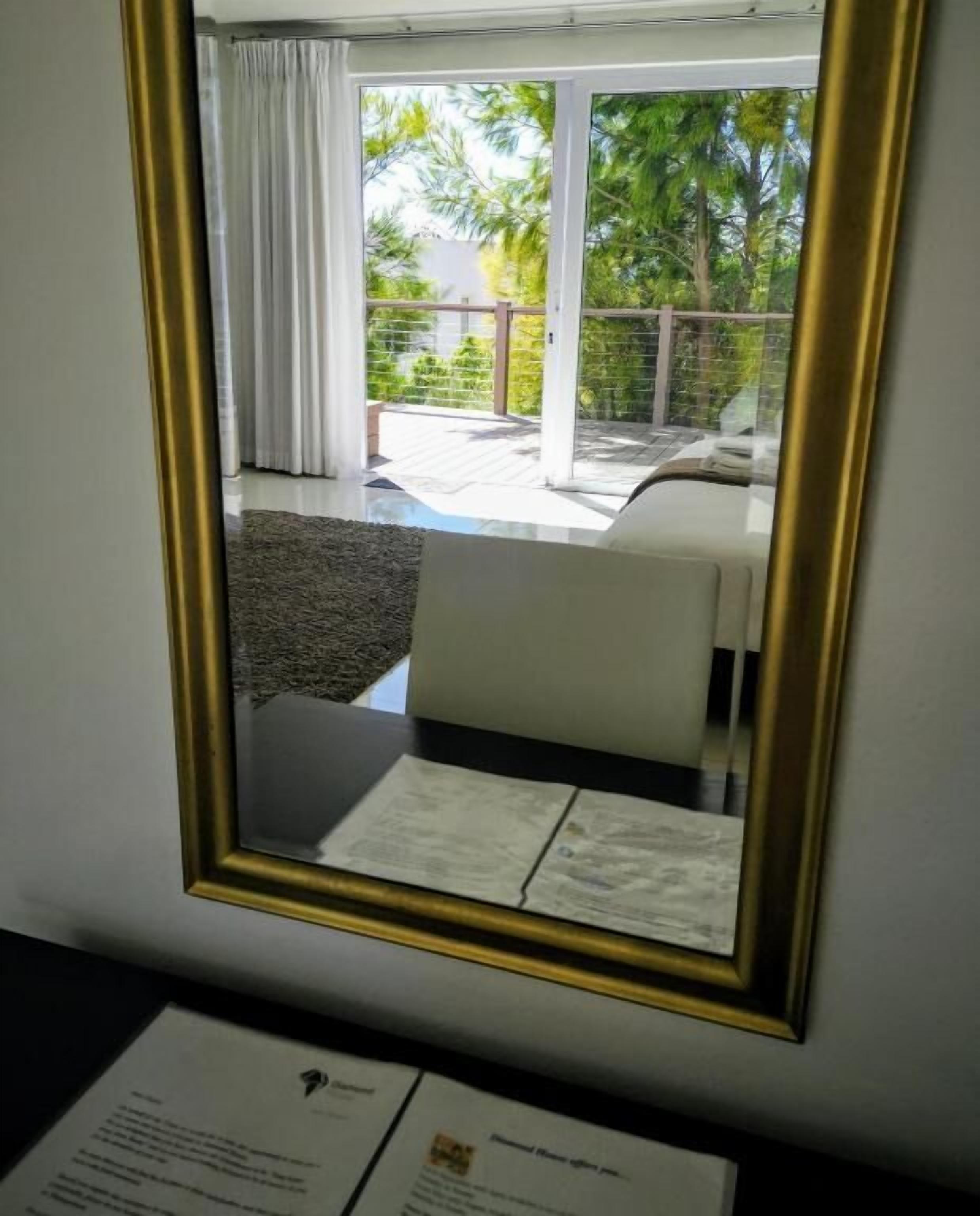 Una habitación con cama, una silla, una mesa y un ventanal con cortinas.