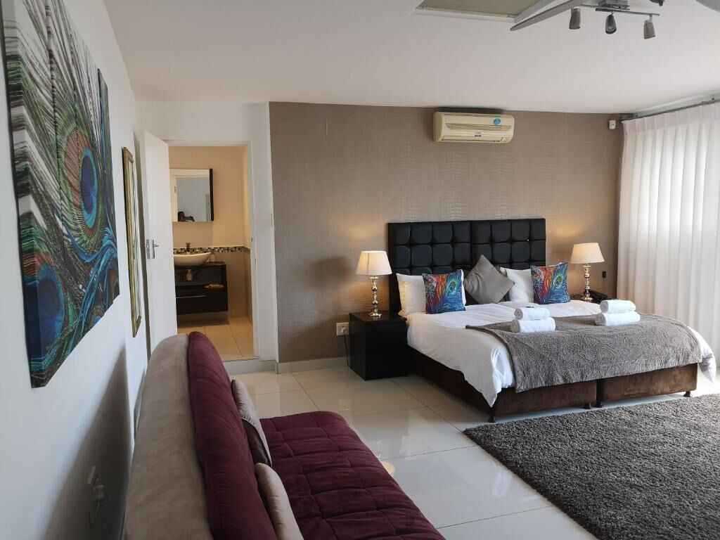 Un dormitorio con cama, mesitas de noche, aire acondicionado de pared y un cuadro grande.