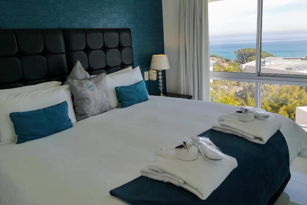 Une chambre d’hôtel avec un grand lit, une vue sur l’océan et un design moderne.